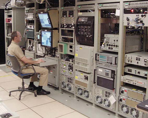 A submarine radio room with racks of equipment, and a military PDU at the top of each rack.